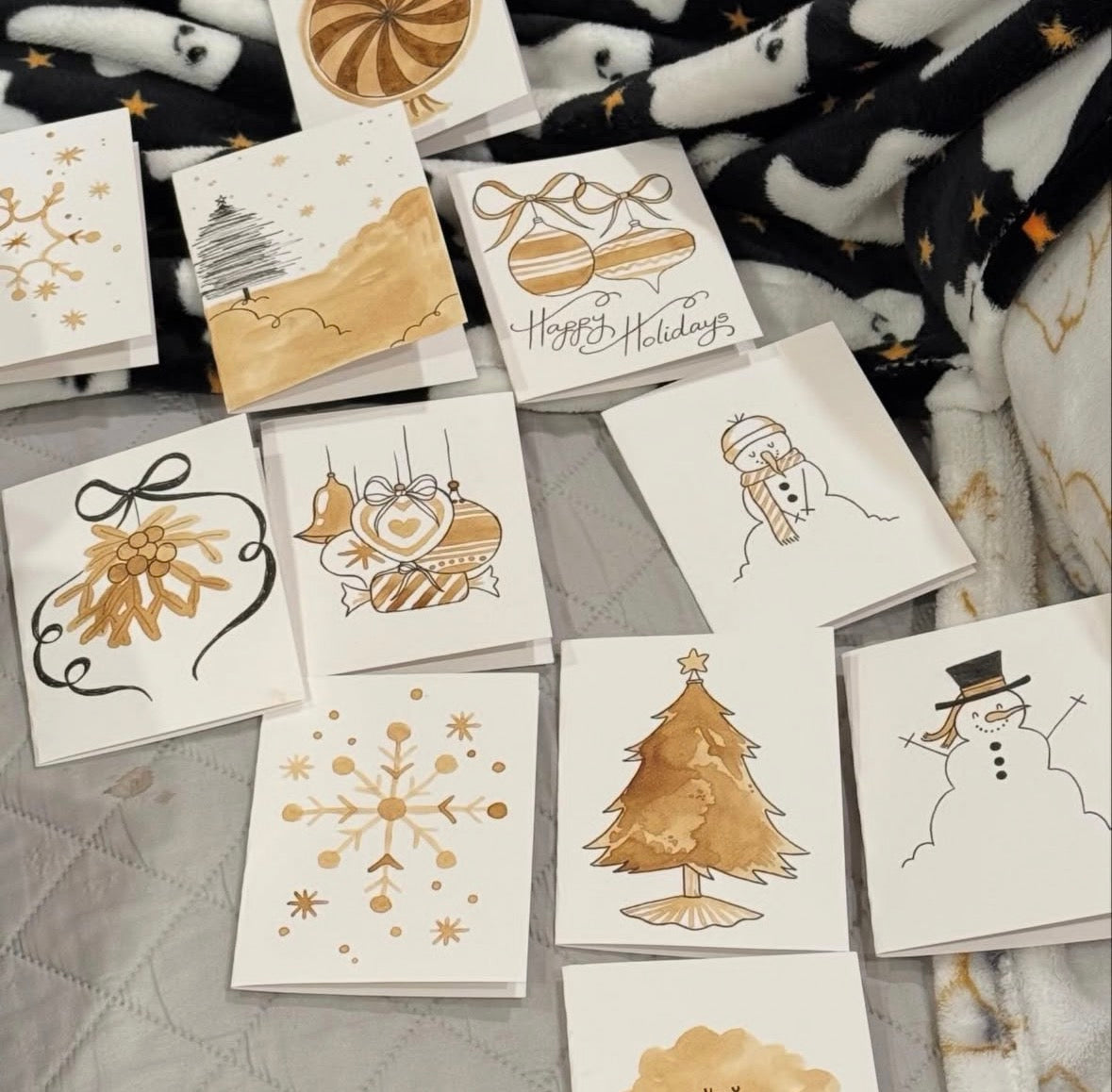 Collection of hand-painted holiday greeting cards with snowflakes, ornaments, and Christmas trees